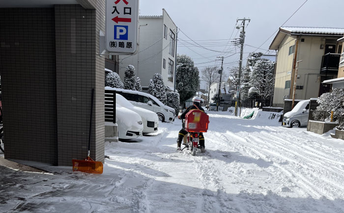 バイクで配達する郵便局員